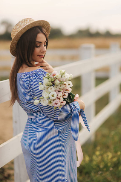 Charming pregnant woman hold a bouquet of flowers. Happy woman smile. Future mother in nature - Zdjęcie, obraz