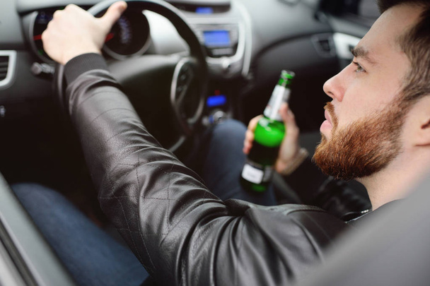 Man with a bottle of beer driving a car - Photo, image