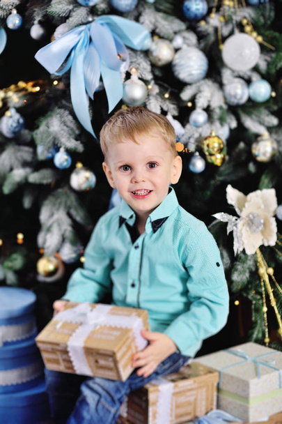 babyjongen opent dozen met cadeaus onder de kerstboom - Foto, afbeelding