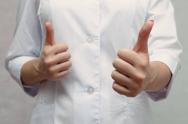 Nurse in medical gown is showing a thumbs up gesture. Good treatment result. - Fotoğraf, Görsel