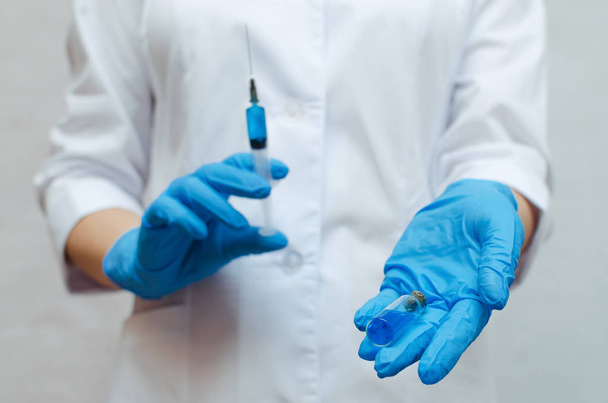 Syringe with a blue medical drug in the doctor hands dressed in the medical gown. - Fotoğraf, Görsel