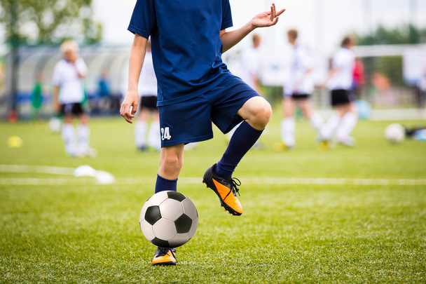 10 代の若者少年サッカー サッカーの試合を再生します。若いフットボール選手を実行し、サッカーのピッチでサッカー ボールを蹴る. - 写真・画像