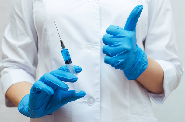 Syringe with a blue medical drug and doctor hand which showing a thumbs up sign. The best medical drug concept. - Фото, изображение