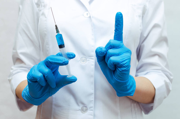 Syringe with a blue medical drug and doctor hand which showing up what means attention. - Фото, зображення
