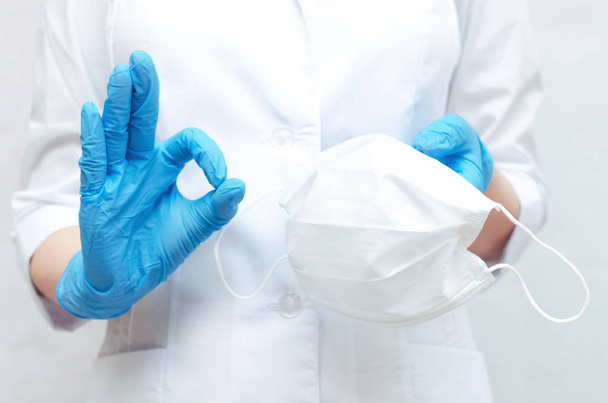 Masque médical dans les mains du médecin vêtu des gants médicaux bleus. Utilisez un masque médical pour prévenir une maladie
. - Photo, image