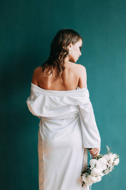 Conceptual wedding, the morning of the bride in the European style. Boudoir dress and a bouquet of flowers, fees in the interior Studio. - Foto, afbeelding