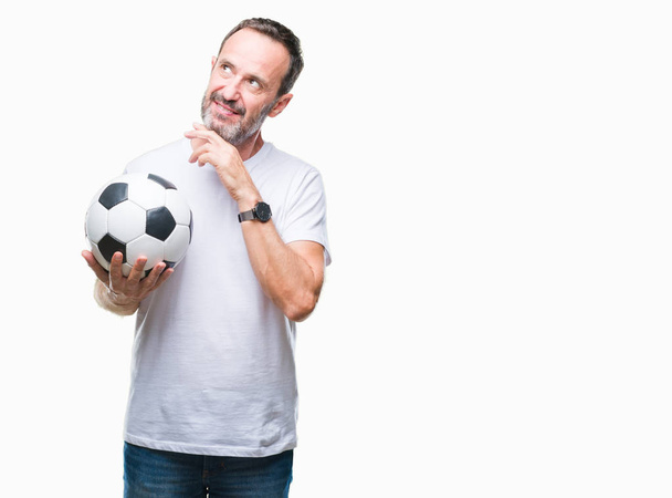 Middle age hoary senior man holding soccer football ball over isolated background serious face thinking about question, very confused idea - Foto, immagini