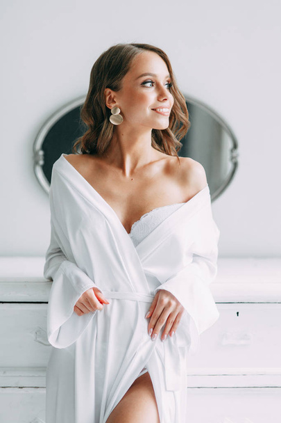 Conceptual wedding, the morning of the bride in the European style. Boudoir dress and a bouquet of flowers, fees in the interior Studio. White minimalism for the bride - Foto, imagen