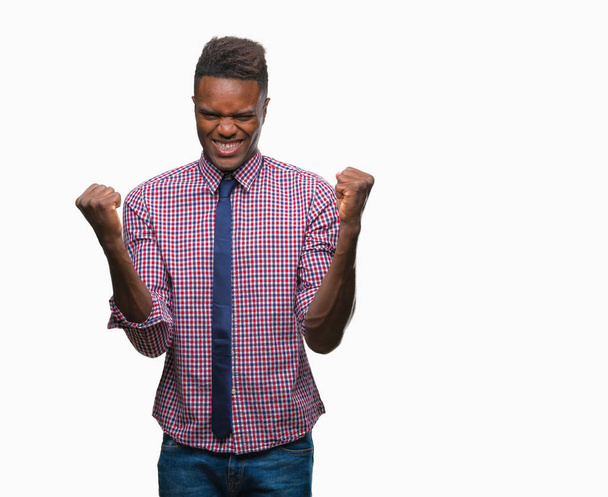 Mladí africké americké obchodní muž nad izolované pozadí slaví překvapil a ohromilo pro úspěch s náručí vystouplý a otevřené oči. Vítěz koncept. - Fotografie, Obrázek