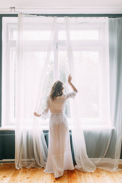 Conceptual wedding, the morning of the bride in the European style. Boudoir dress and a bouquet of flowers, fees in the interior Studio. White minimalism for the bride - Foto, afbeelding
