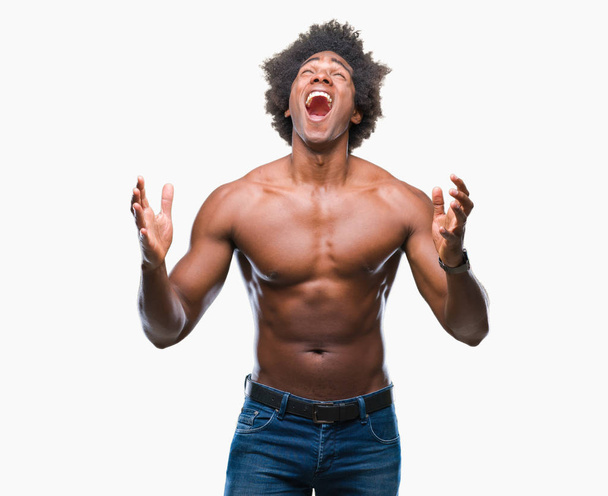 Hombre afroamericano sin camisa mostrando cuerpo desnudo sobre fondo aislado loco y loco gritando y gritando con expresión agresiva y los brazos levantados. Concepto de frustración
. - Foto, imagen