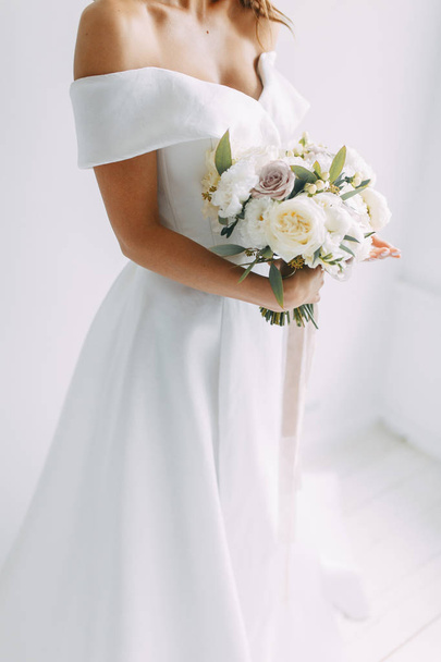A concept wedding, contemporary European bride. Bouquet of flowers, fees in the interior Studio. Ideas for a minimalist wedding, white color - Foto, afbeelding