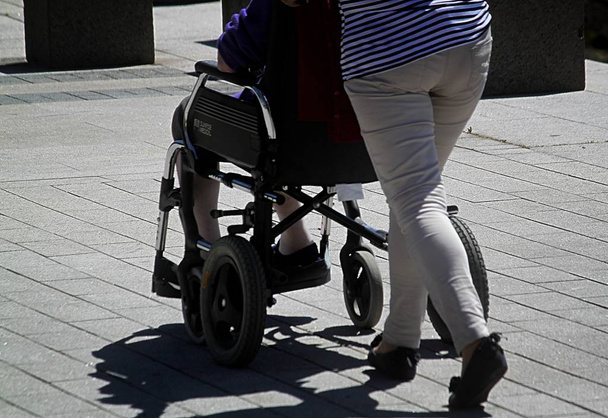 la persona anziana a carico sulla sedia a rotelle è guidata da un
 - Foto, immagini