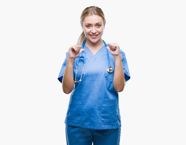Jonge blonde chirurg dokter vrouw over geïsoleerde achtergrond op zoek vertrouwen met glimlach op het gezicht, wijzen zichzelf met de vingers trots en blij. - Foto, afbeelding