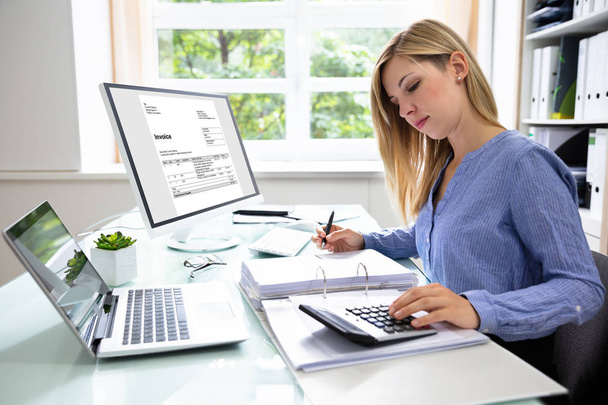 Young Businesswoman Calculating Bill With Computer And Laptop On Desk - Foto, Imagen