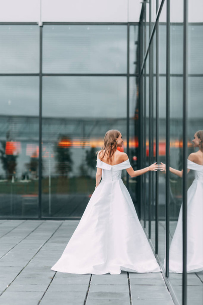 Modern, stylish bride in European dress. Photo shoot on the street near the hotel. Bouquet and strict dress - Φωτογραφία, εικόνα