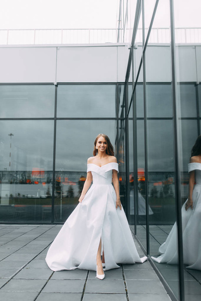 Modern, stylish bride in European dress. Photo shoot on the street near the hotel. Bouquet and strict dress - Φωτογραφία, εικόνα