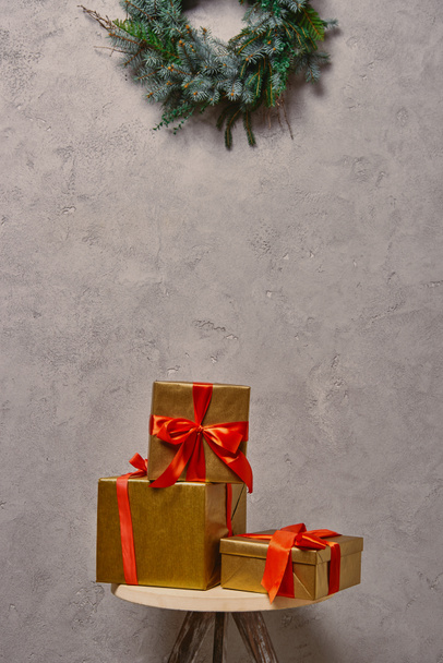 golden Christmas gift boxes on chair under fir wreath in room - Photo, Image