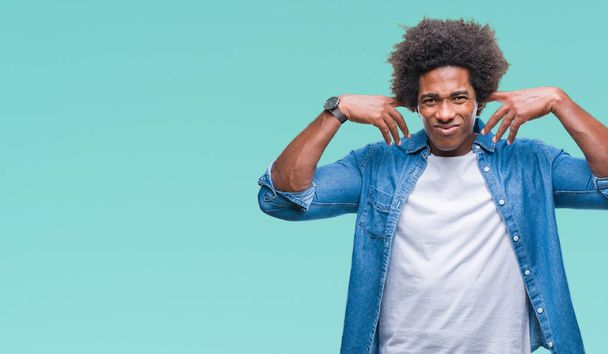 Afro-Amerikaanse man over geïsoleerde achtergrond die betrekking hebben op oren met vingers met geërgerd expressie voor het geluid van luide muziek. Dove concept. - Foto, afbeelding