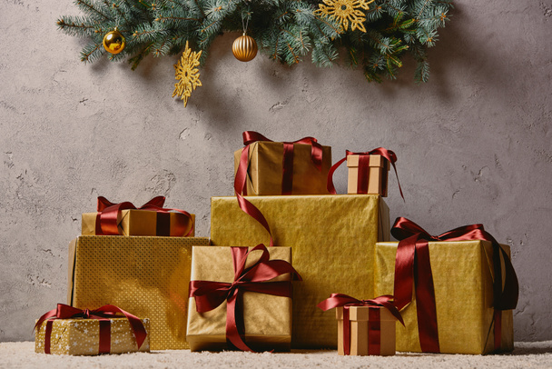pile de boîtes cadeaux de Noël doré sur le tapis dans la chambre sous l'arbre de Noël
 - Photo, image