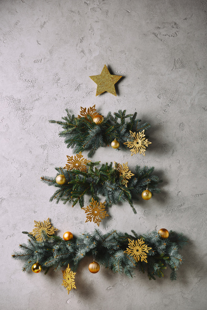 árbol de Navidad hecho a mano y estrella colgando en la pared gris en la habitación
 - Foto, Imagen