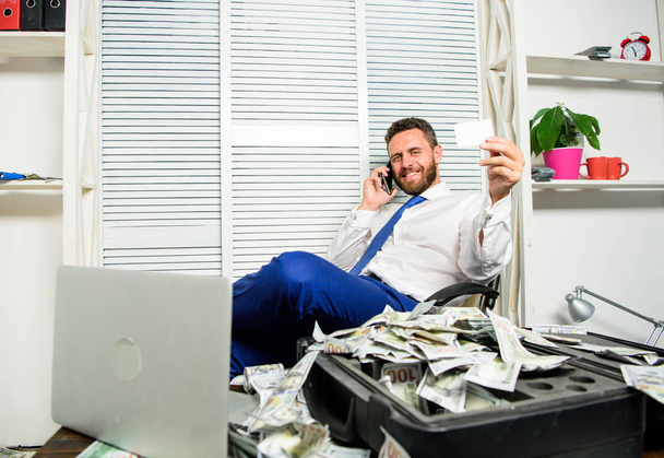 Man successful businessman phone conversation ask service. Businessman rich bearded guy sit office with lot of cash money. Bank loan or credit. Get cash in few minutes. Man hold plastic bank card - Fotografie, Obrázek