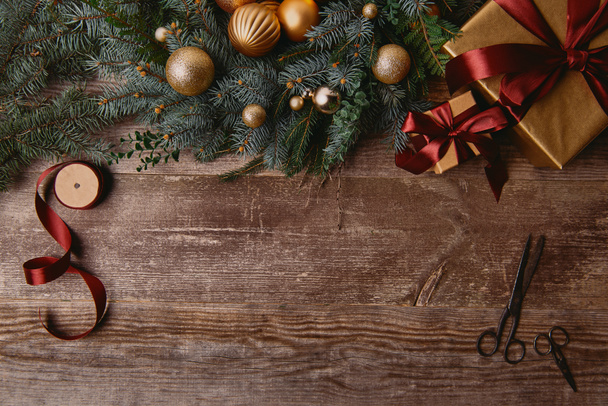 vista superior de las cajas de regalo de Navidad, corona de abeto, carrete de cinta y tijeras en la mesa de madera
 - Foto, Imagen