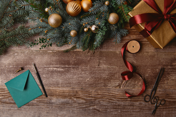 木製のテーブルでクリスマス ギフト ボックス、モミのリース、リボン スプール、封筒の上から見る - 写真・画像