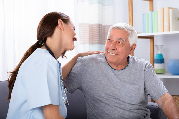 Ritratto di felice uomo anziano e infermiera seduta sul divano
 - Foto, immagini