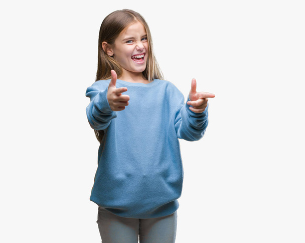 Mooi meisje winter trui dragen over geïsoleerde achtergrond wijzen vingers naar camera met gelukkig en grappig gezicht. Goede energie en vibrafoon. - Foto, afbeelding