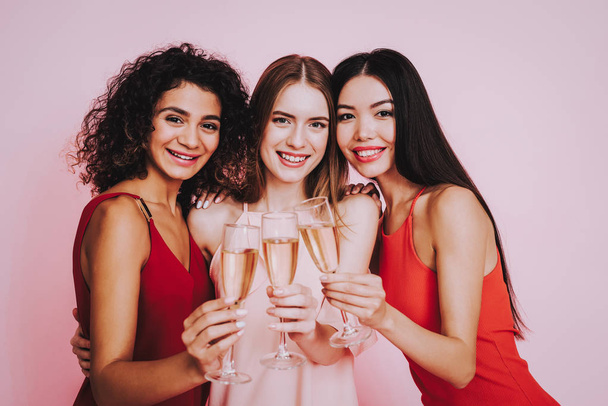Pink and Red Dresses. Pink Background. Celebrating Women's Day.Three Emotional Women. Happy Woman. Glasses Champagne. International Party. Beautiful Woman. Womans Emotion. Girls with Champagne. - Photo, image