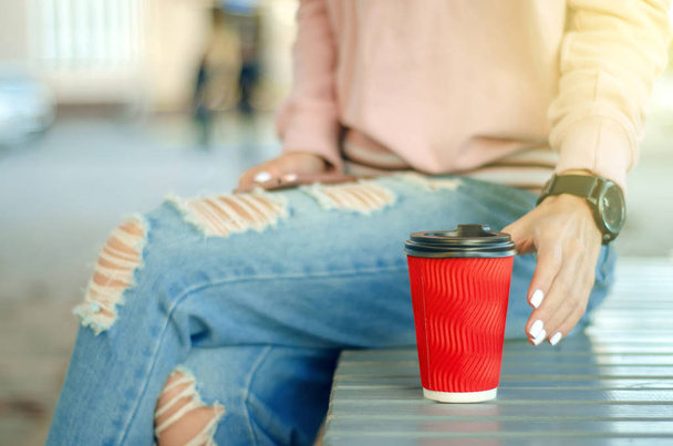 Beautiful woman in jeans and a sweatshirt with coffee smartphone mobile phone - Foto, imagen