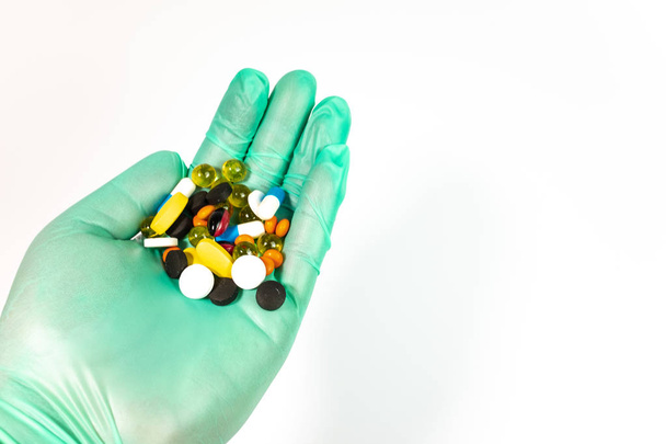 hand in medical glove holding pills on white background - Valokuva, kuva