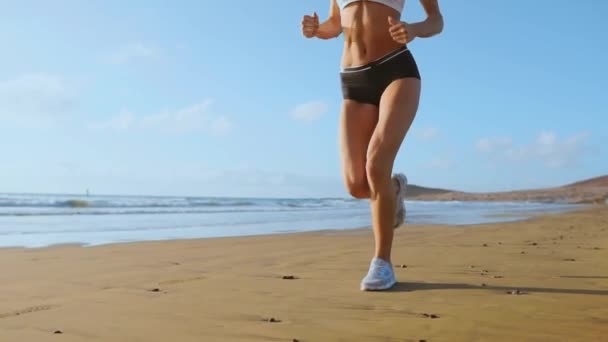 Mooie vrouw in sport korte broek en t-shirt draait op het strand met wit zand en blauwe oceaanwater op het eiland in slow motion. Golven en zand heuvels op de rug won - Video