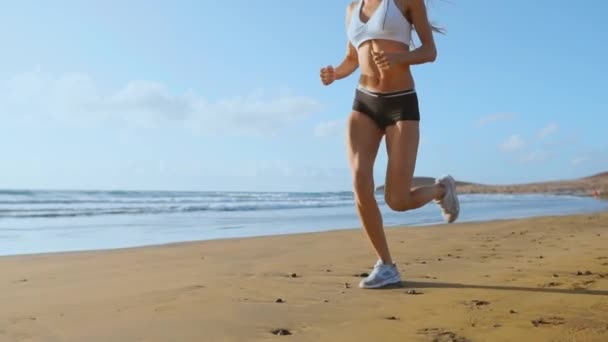 Mulher bonita em shorts esportivos e camiseta correndo na praia com areia branca e água azul do oceano na ilha em câmera lenta. Ondas e colinas de areia nas costas ganhou
 - Filmagem, Vídeo