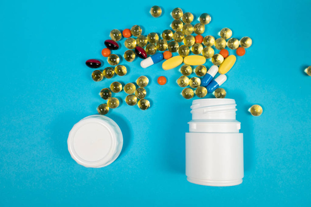 Various pills in bottle on blue background - Foto, imagen