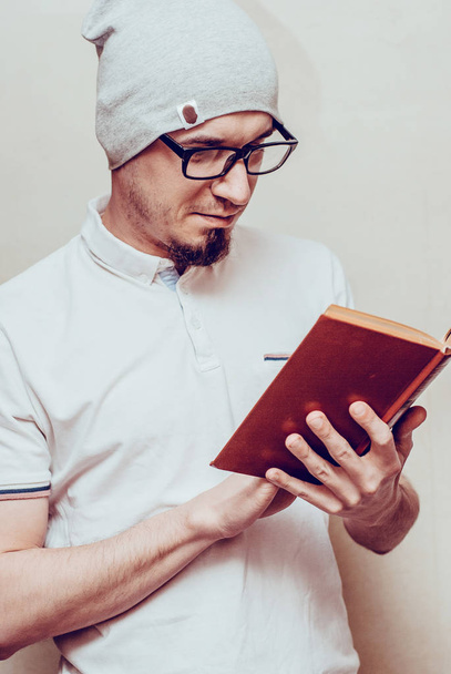 Portrait of handsome bearded man wearing glasses white shirt, reading book. Horizontal, film effect. - Photo, Image