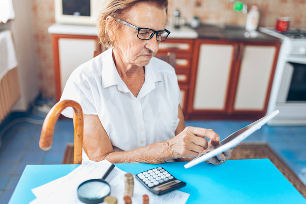 Senior woman at home checking her finances and investments - 写真・画像