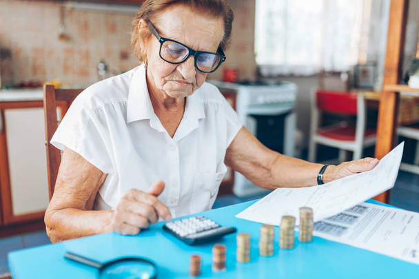 Senior woman at home checking her finances and investments - Foto, afbeelding
