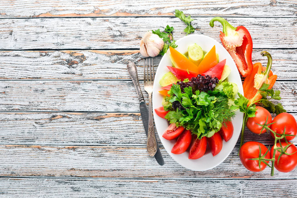 A plate of sliced fresh vegetables. Salad. On the old wooden background. Free space for text. Top view. - Photo, Image