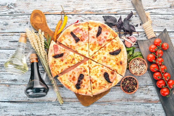 Pizza with bacon, smoked tomatoes and mozzarella cheese. Italian cuisine. On a wooden background. Free space for text. Top view. - 写真・画像