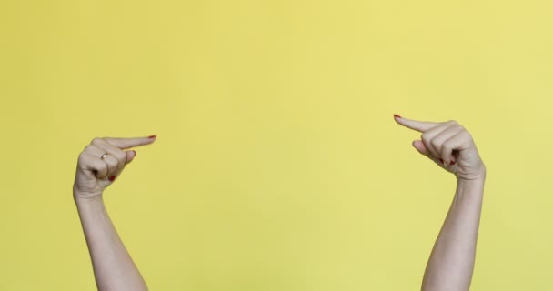 Vrouwelijke handen gebaren op iets op gele achtergrond. - Video