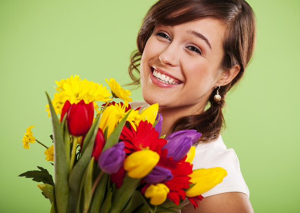 Portrait of a smiling woman with colorful flowers - Photo, Image