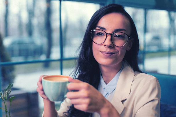 Cheerful young woman enjoying her morning coffee - Fotografie, Obrázek