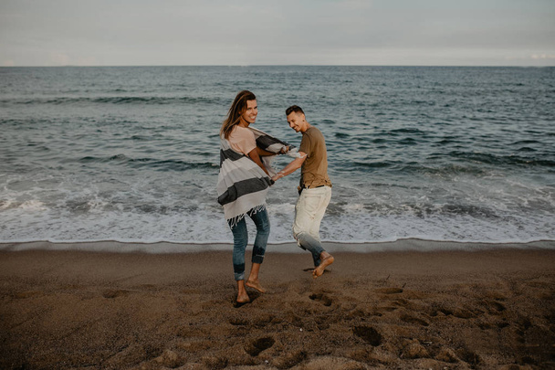 Happy couple in love walking on the beach - Zdjęcie, obraz