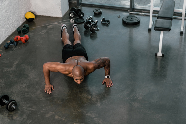 vysoký úhel pohledu svalové shirtless mladý muž dělá push up v tělocvičně  - Fotografie, Obrázek