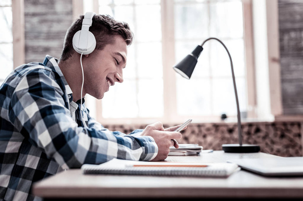 Handsome student listening to music while doing homework - Photo, Image