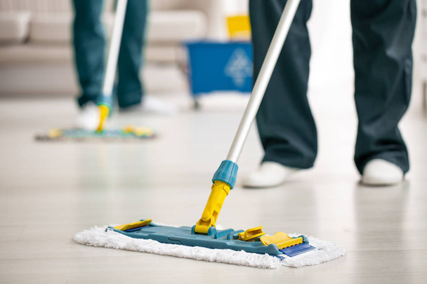 Close-up on mop on the floor holding by cleaning specialist while purifying interior - Foto, immagini