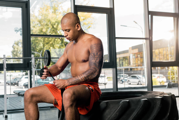 deportista afroamericano sin camisa envolviendo la mano en venda de boxeo en el gimnasio
 - Foto, Imagen