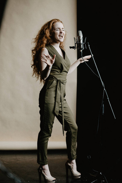 Beautiful singing girl with microphone in studio - Foto, Imagem